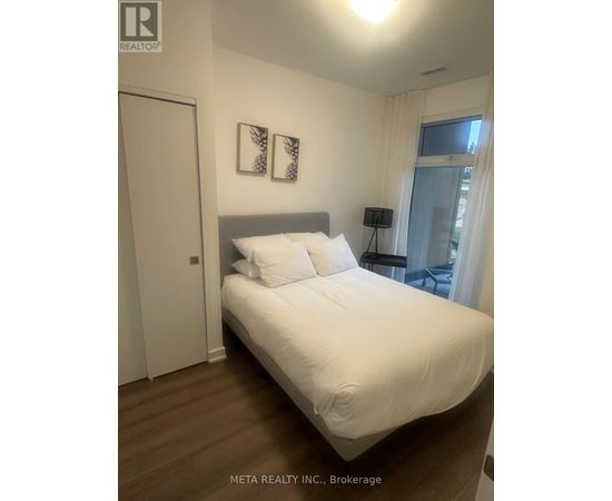 A bedroom with a large bed and two pictures on the wall.