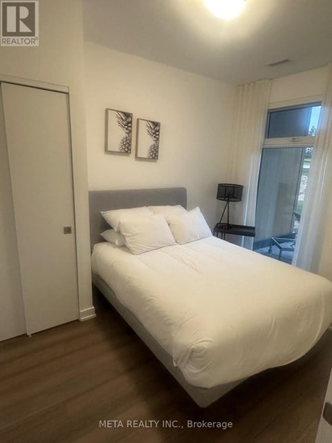 A bedroom with a large bed and two pictures on the wall.