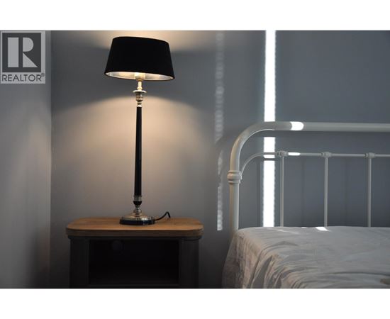 A bedroom with a bed, nightstand and lamp.