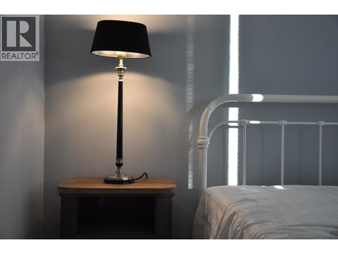 A bedroom with a bed, nightstand and lamp.