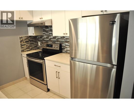 A modern kitchen with a stainless steel refrigerator and oven.