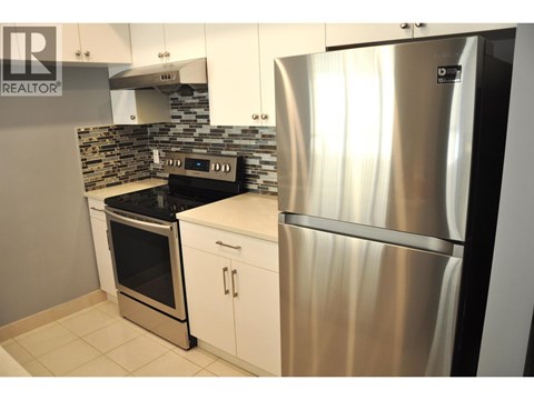 A modern kitchen with a stainless steel refrigerator and oven.