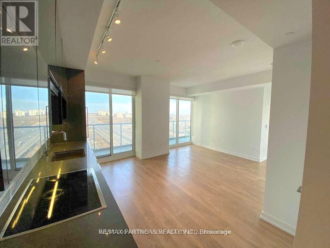 A spacious room with wooden floors and a glass door leading to a balcony.