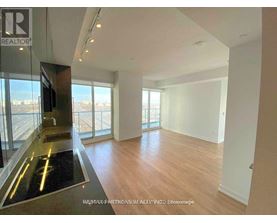A spacious room with wooden floors and a glass door leading to a balcony.