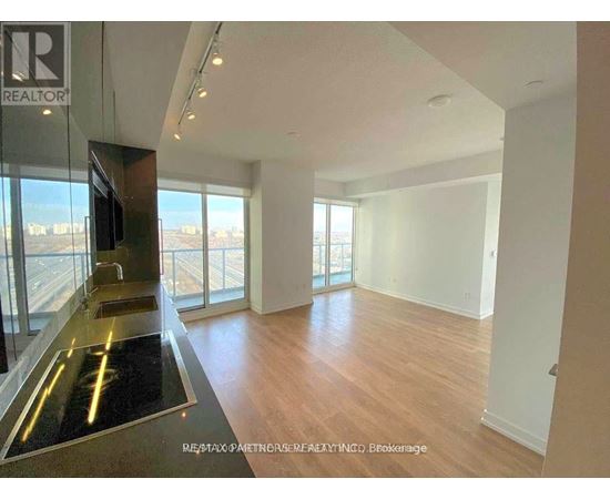 A spacious room with wooden floors and a glass door leading to a balcony.