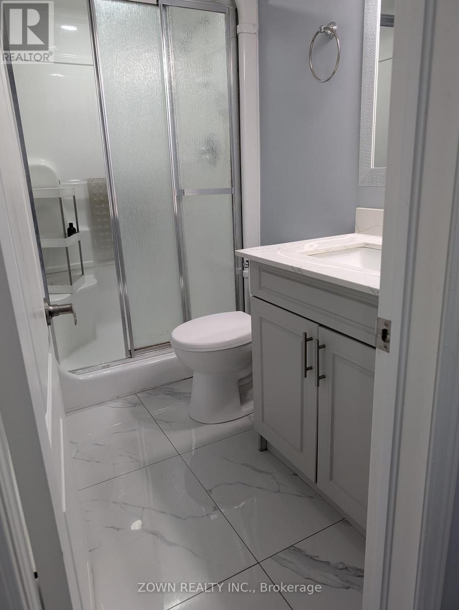 A white bathroom with a toilet, sink, and shower.