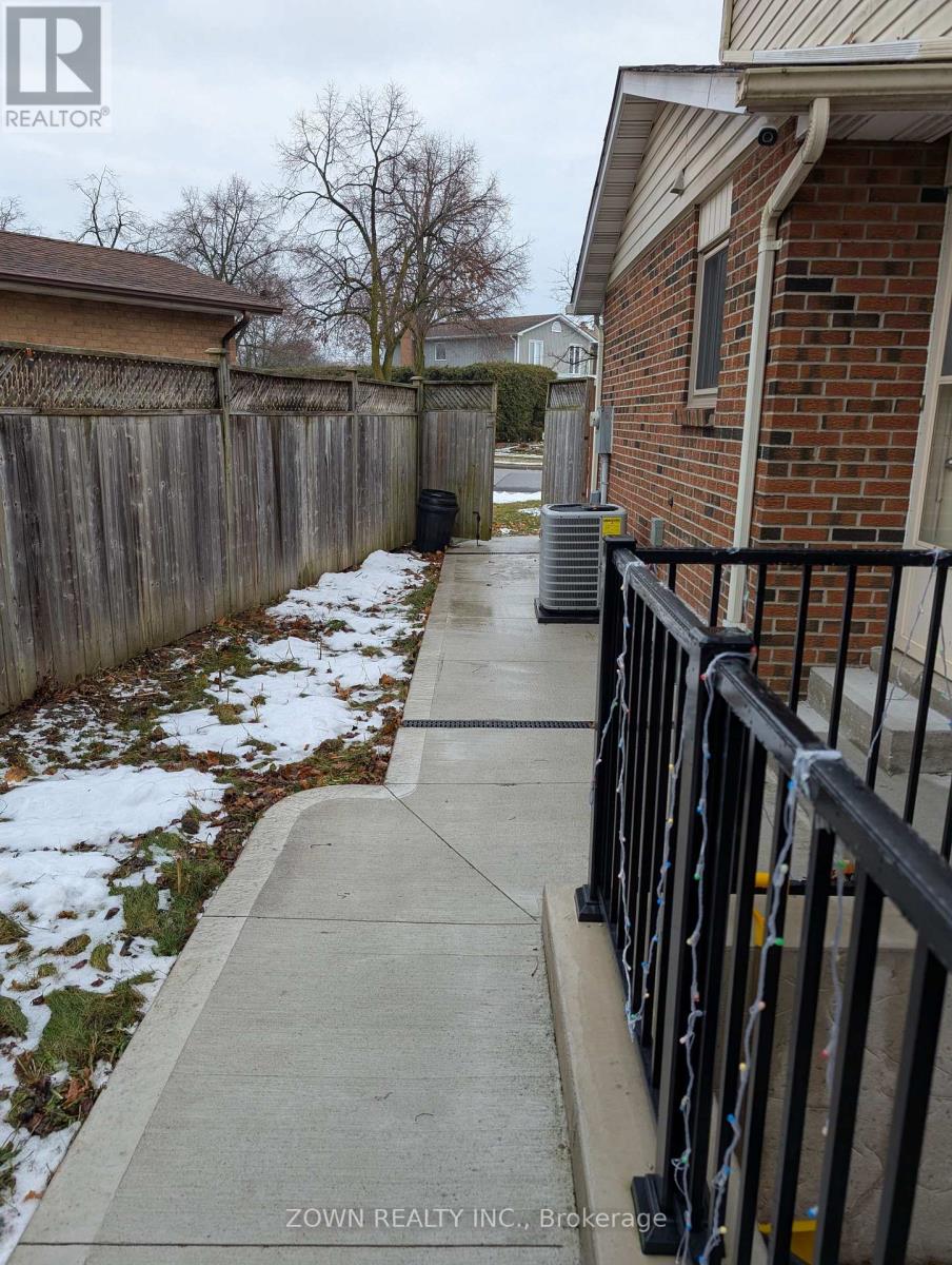 A snowy sidewalk in front of a brick house.
