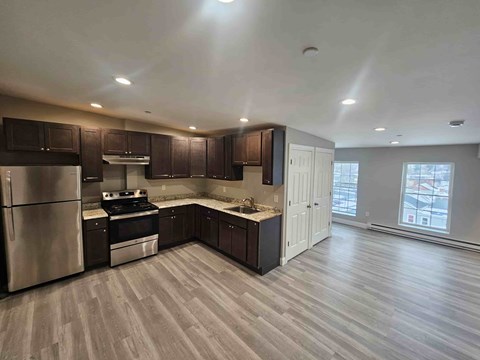 A kitchen with a refrigerator, stove, and cabinets.