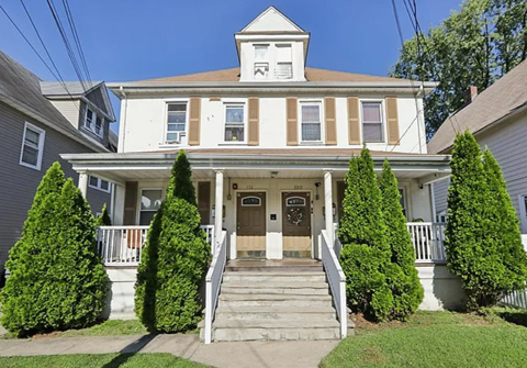 A white house with a brown roof and a brown door.