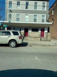 A tan car is parked on the street in front of a building.