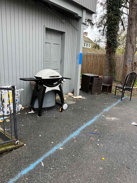 A BBQ grill is leaning against a building.