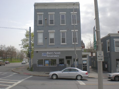 A silver car is parked in front of a Barry Scott Insurance office.