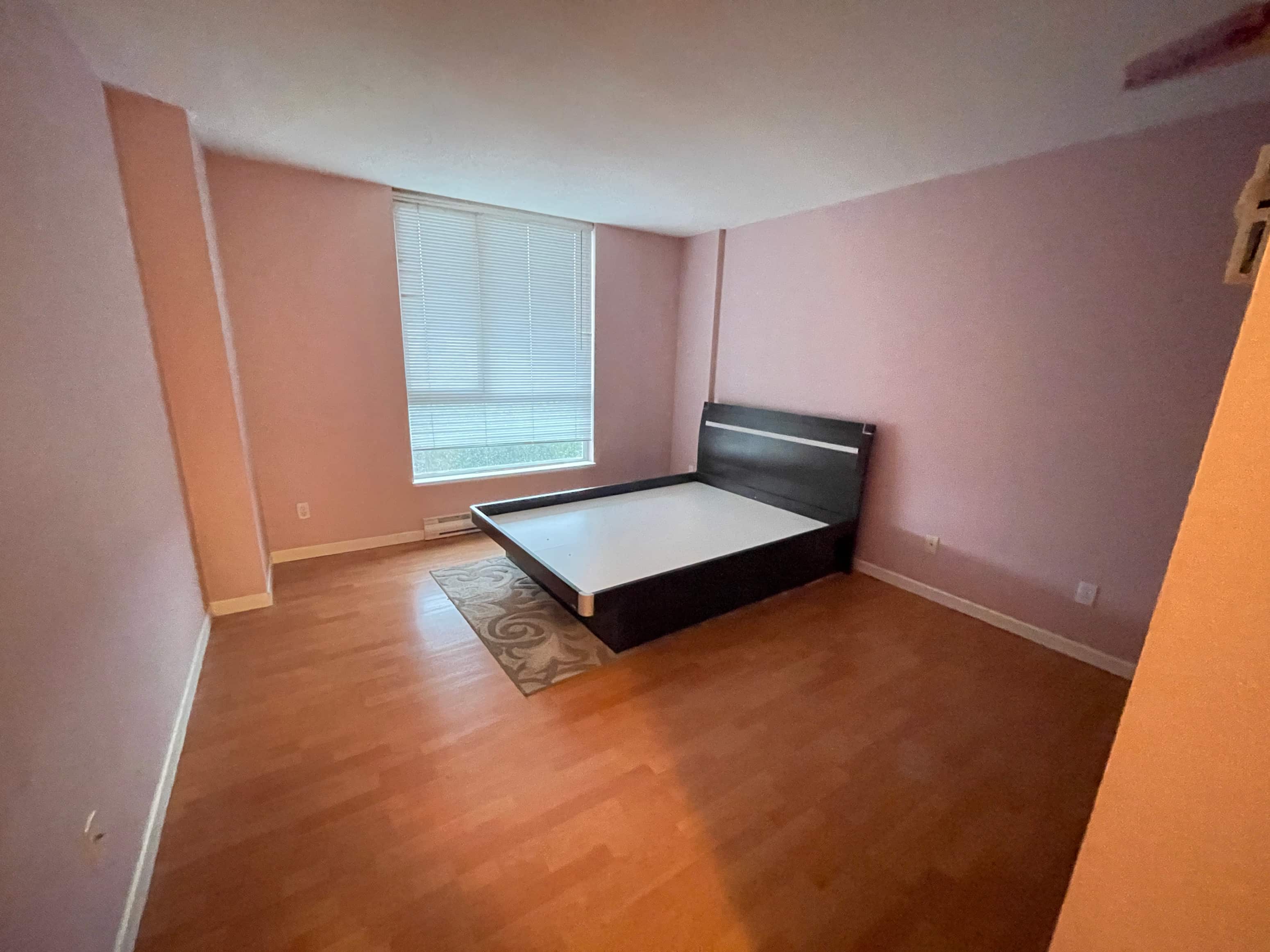 A bedroom with a bed, a rug, and a window.