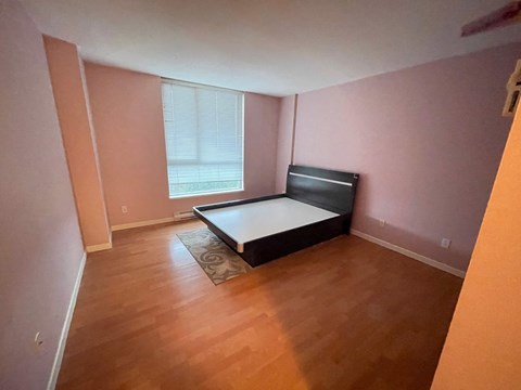 A bedroom with a bed, a rug, and a window.
