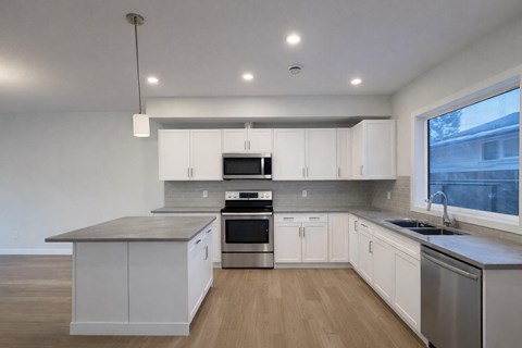 A modern kitchen with white cabinets and stainless steel appliances.