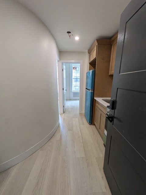 A kitchen with a refrigerator, cabinets, and a counter.