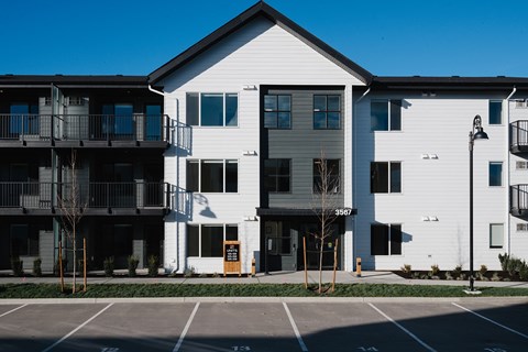 A white building with a black roof and a balcony on the left side.