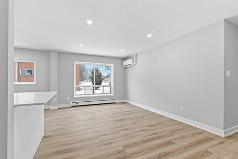 A spacious room with a window and a white counter on the left side.