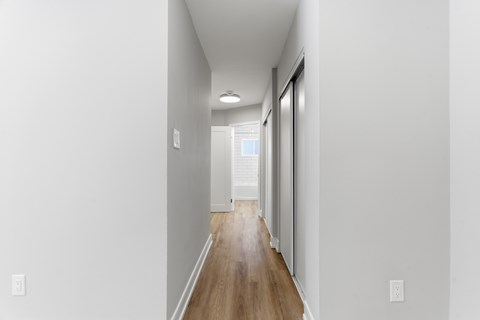 A long hallway with a wooden floor and white walls.