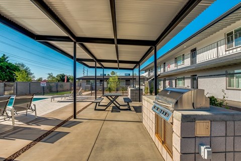 A patio with a table and chairs under a roof.