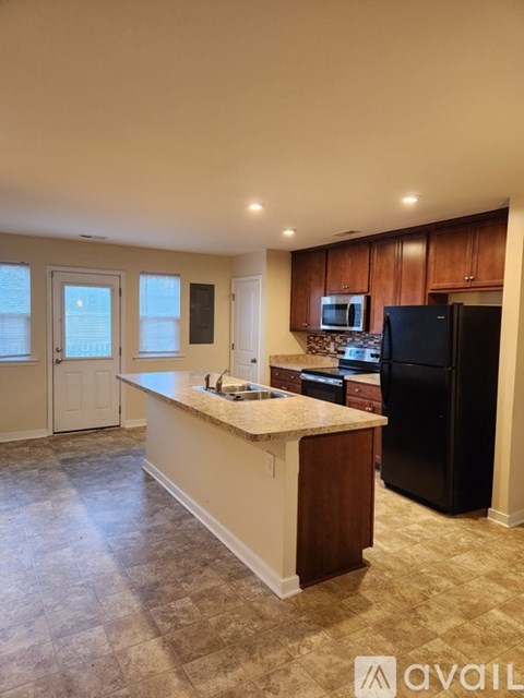 A kitchen with a black refrigerator and a countertop with a sink.