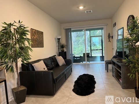 A living room with a black couch and a large window.