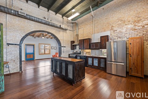 A kitchen with wooden floors and a brick wall.