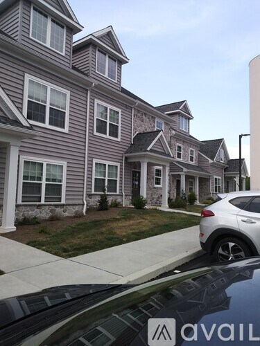 A house with a grey and white exterior and a car parked in front.