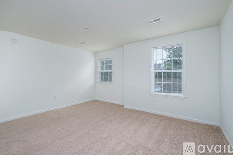 A room with a carpeted floor and a window with blinds.