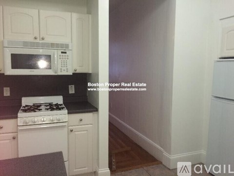 A kitchen with white cabinets and a black countertop.