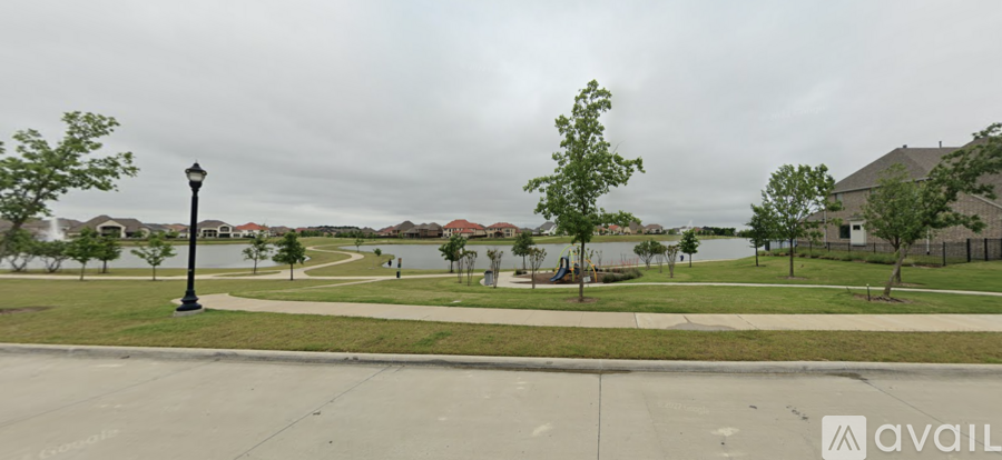 A park with a lake and a fence in the background.