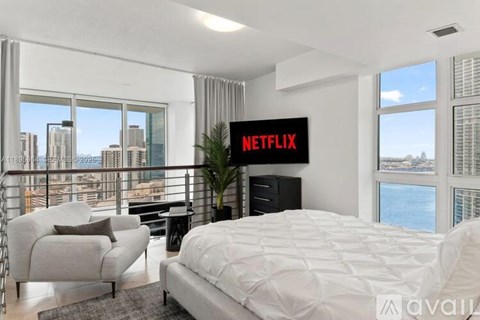 A bedroom with a large bed, a chair, and a Netflix sign on the wall.