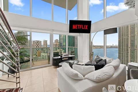 A living room with a white couch and a large window overlooking the city.