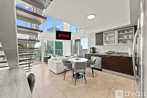 A modern kitchen with a dining table and chairs, a refrigerator, and a large window with a view of the city.