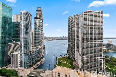 A cityscape with tall buildings and a body of water in the foreground.