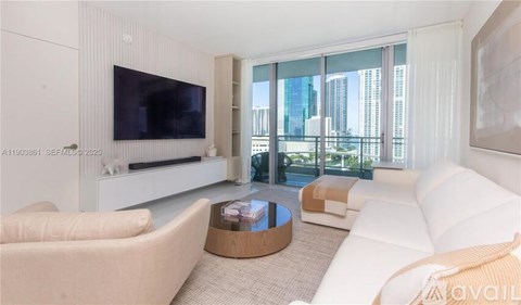 A living room with a white couch, a coffee table, and a flat screen TV.
