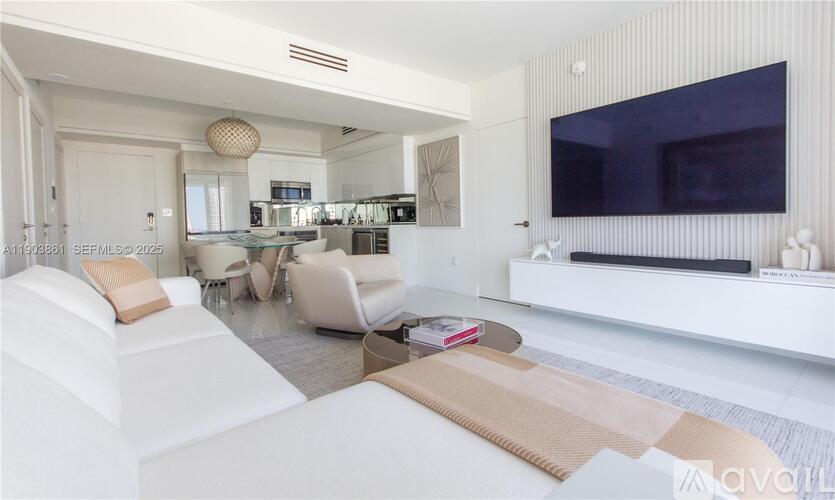 A modern living room with white furniture and a flat screen TV mounted on the wall.