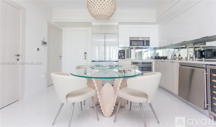 A modern kitchen with a glass table and white chairs.