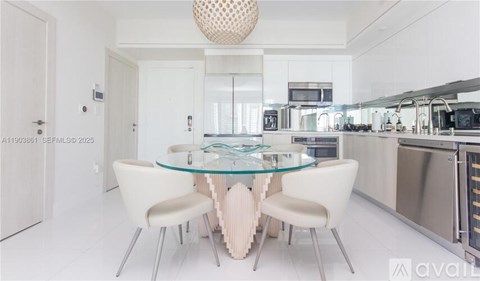 A modern kitchen with a glass table and white chairs.