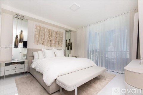 A white bedroom with a large bed and a mirror on the wall.