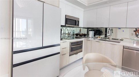 A modern kitchen with white cabinets and a glass-fronted fridge.