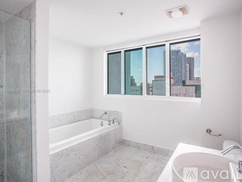 A bathroom with a tub, sink and window.