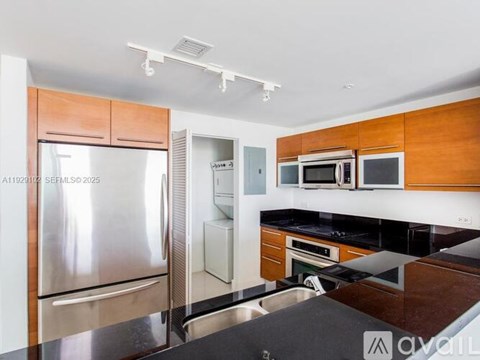 A kitchen with a refrigerator, microwave, and oven.