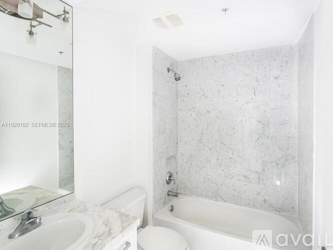 A white bathroom with a marble wall and a white tub.