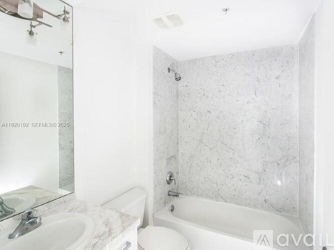 A white bathroom with a marble wall and a white tub.