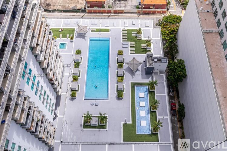 An aerial view of a pool surrounded by buildings and greenery.