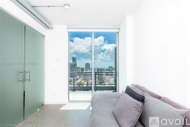 A modern living room with a view of the cityscape outside the window.