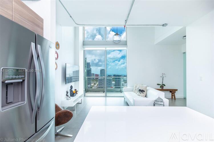 A modern kitchen with a refrigerator and a view of the city through the window.