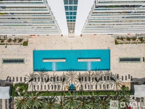 A large swimming pool surrounded by palm trees and lounge chairs.