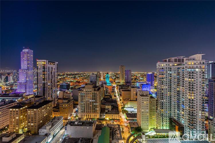 A cityscape at night with tall buildings and bright lights.